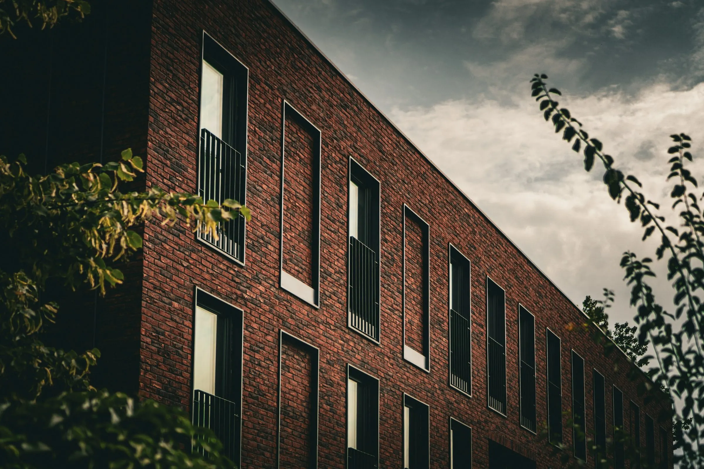 Contemporary brick housing with tall windows under a dramatic evening sky