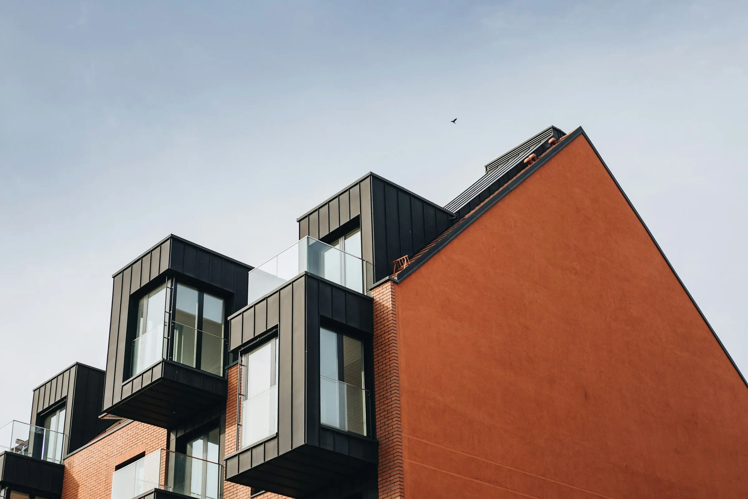 Contemporary housing with dark clad dormers set against a terracotta brick gable