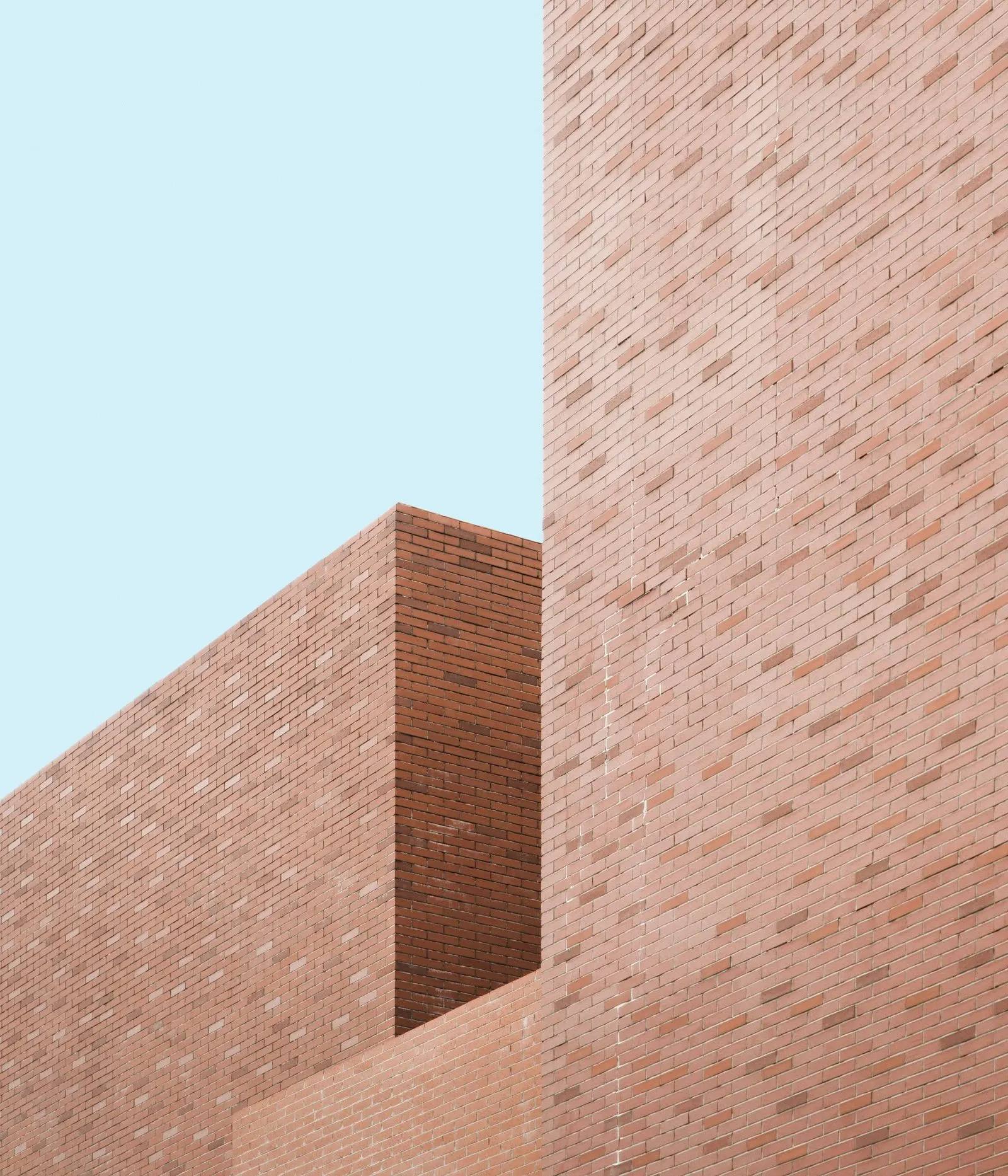 Two clean-lined brick building volumes against a pale sky