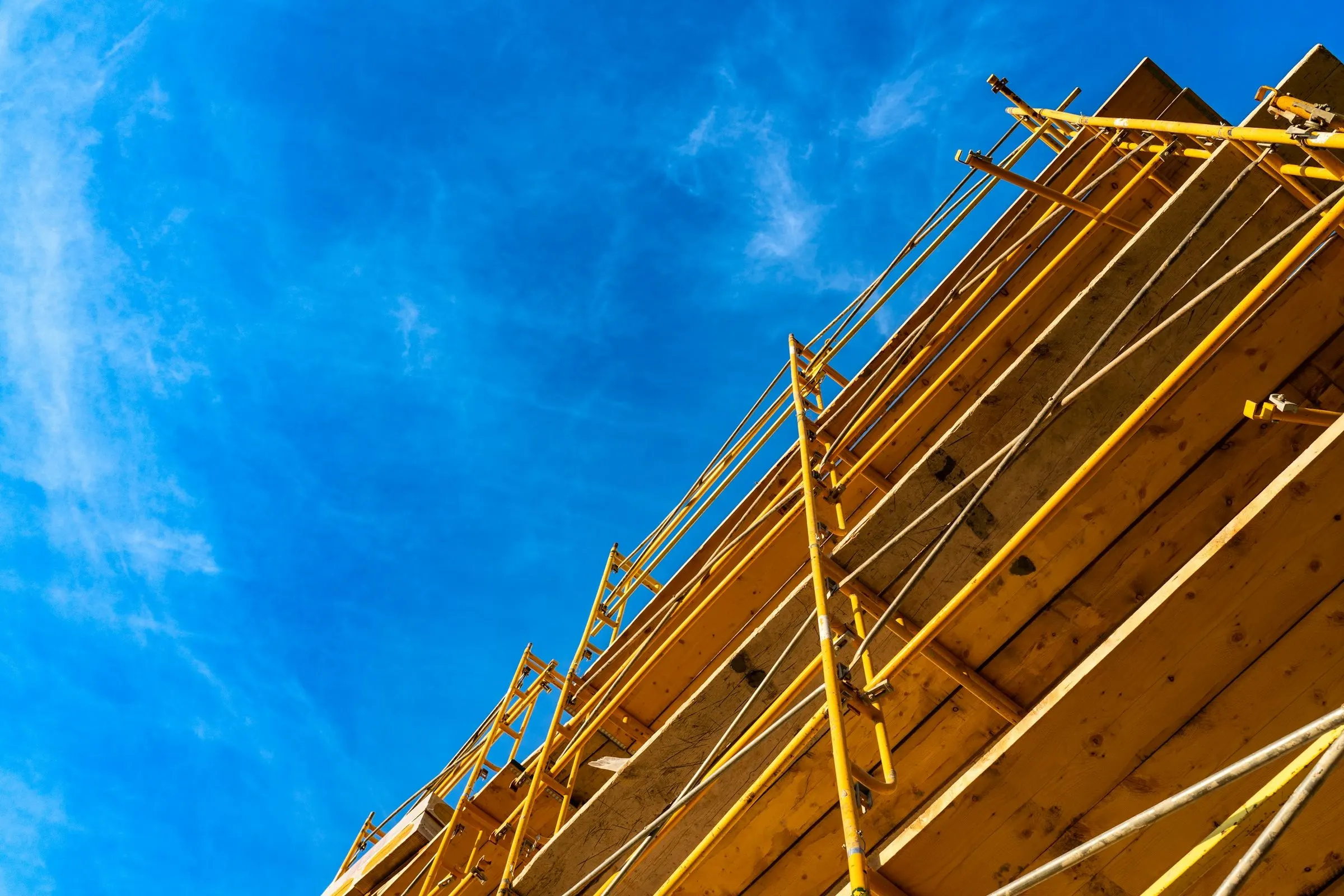 Timber frame and scaffolding of a building under construction set against a deep blue sky